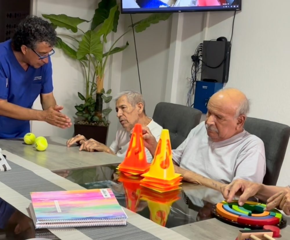 Un terapeuta guía a dos residentes en un ejercicio de terapia ocupacional